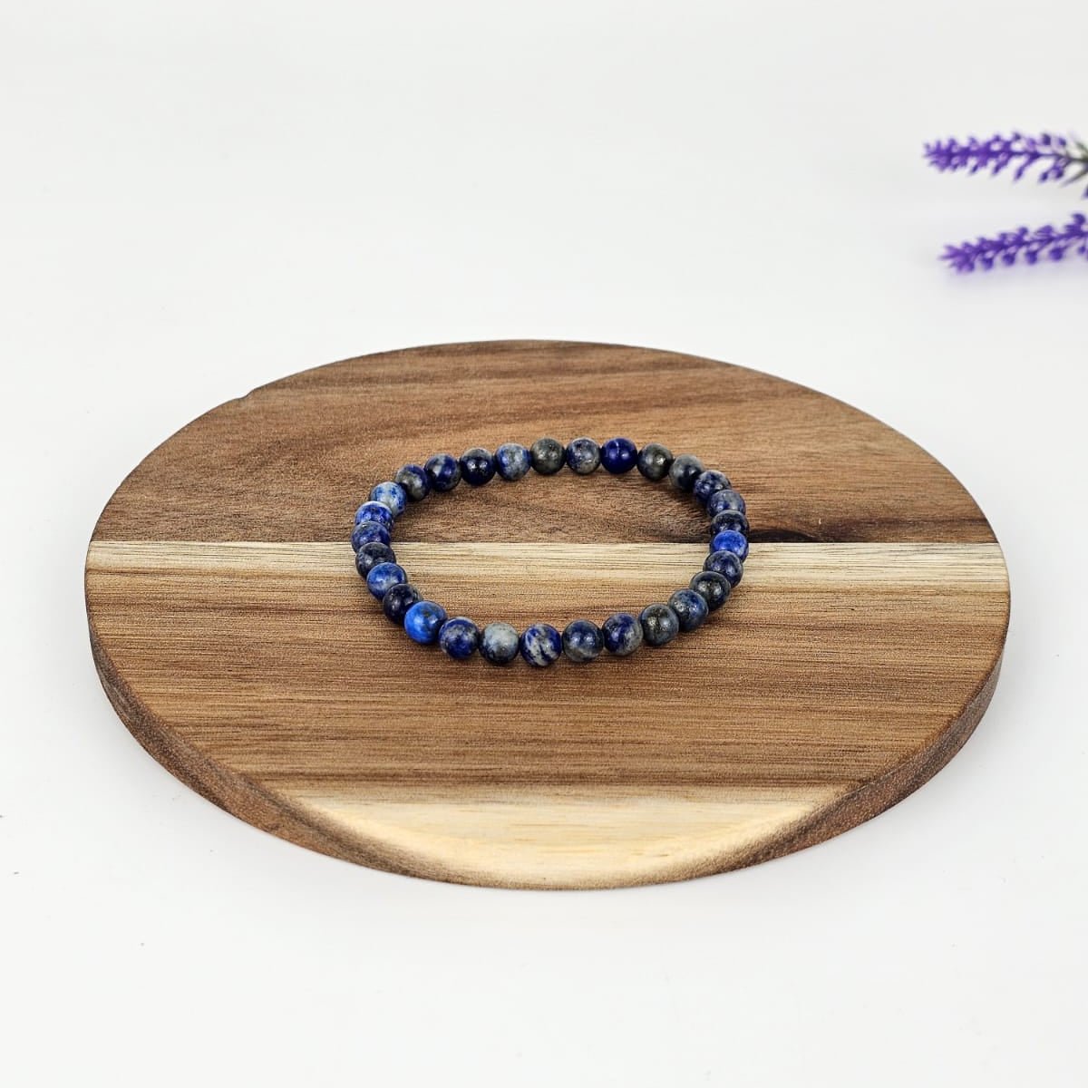 Lapis lazuli beaded bracelet on a wooden plate and a white background