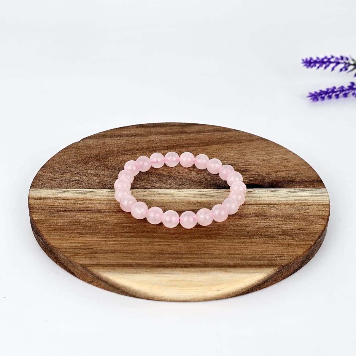 Rose Quartz beaded bracelet on a wooden plate and a white background