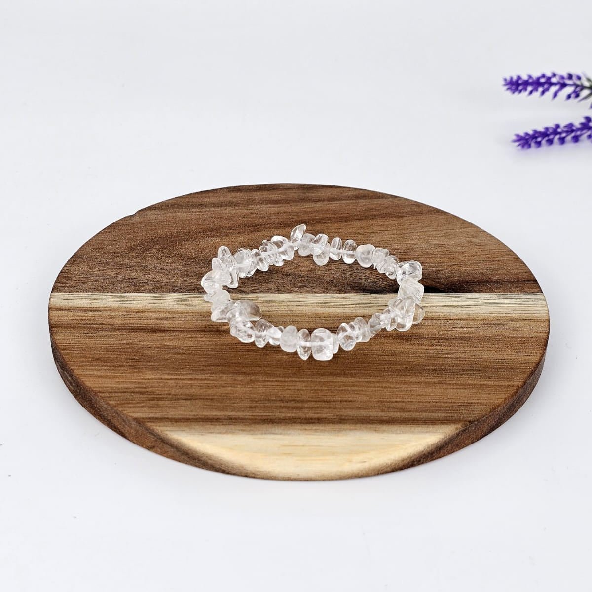 Clear quartz chip bracelet on a wooden plate with a white background