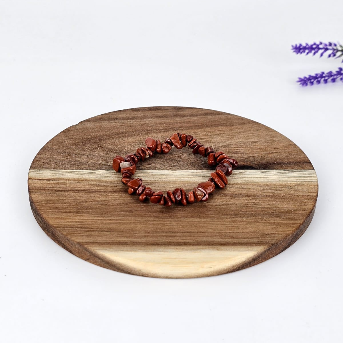 Red jasper chip bracelet on a wooden plate and a white background