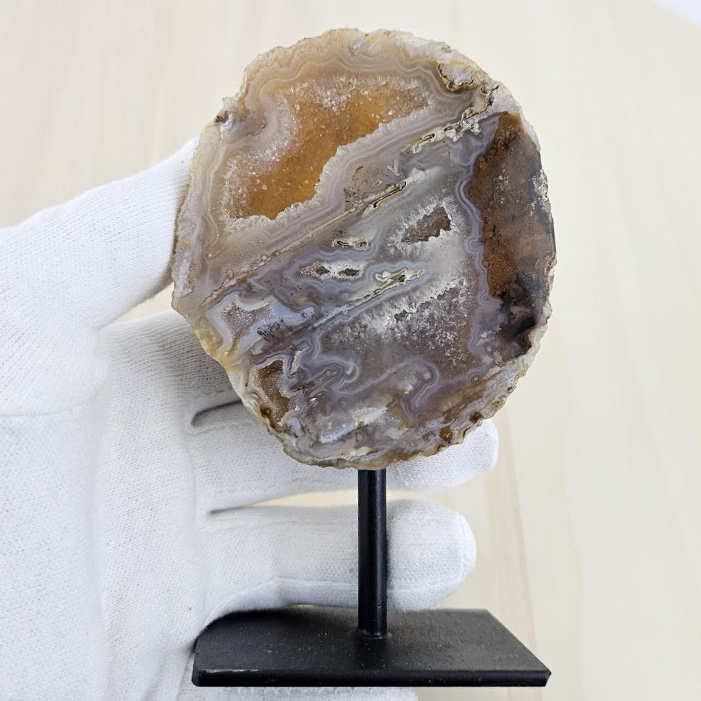 Agate stone on a stand held by a gloved hand against a neutral background