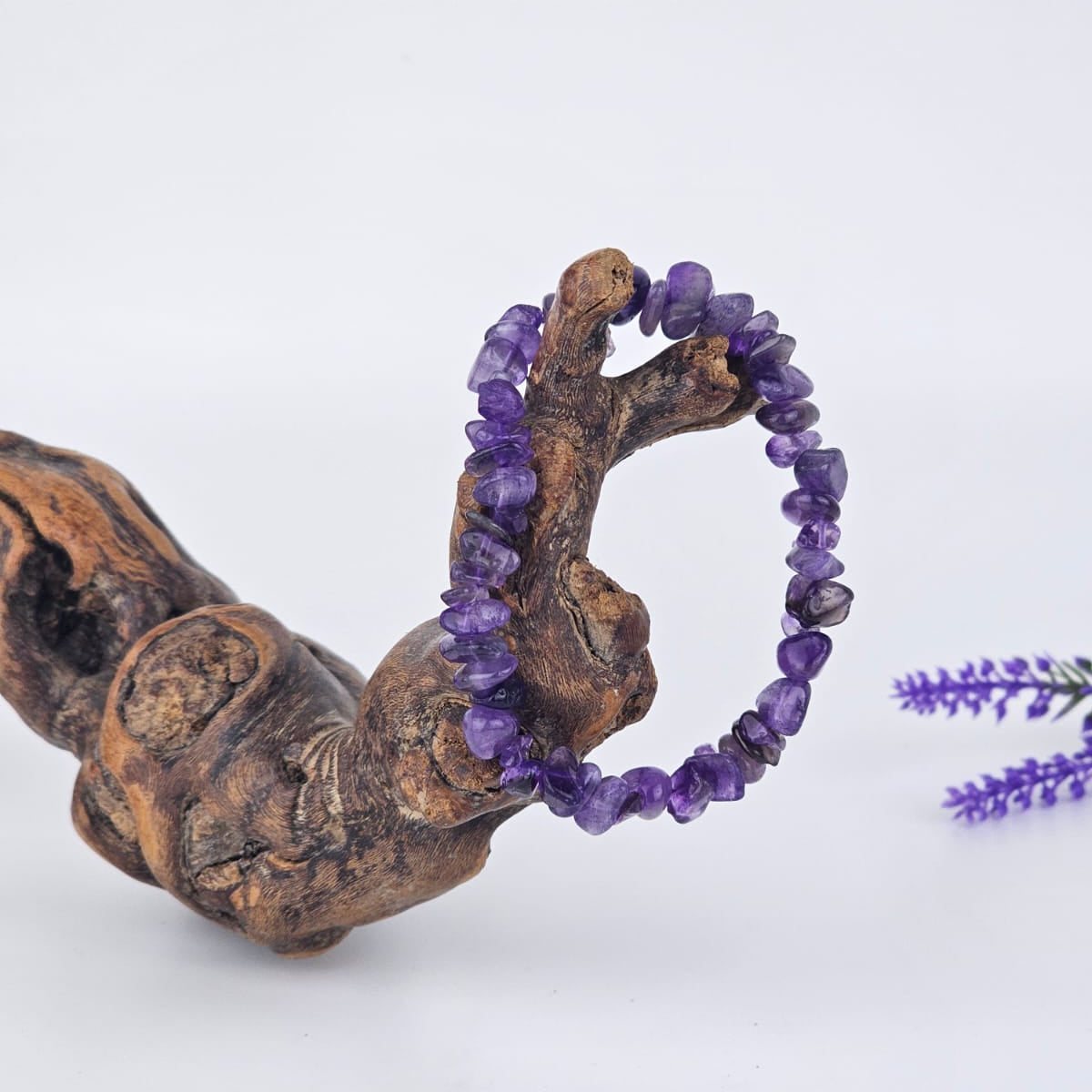 Amethyst chip bracelet on a wooden branch with a white background