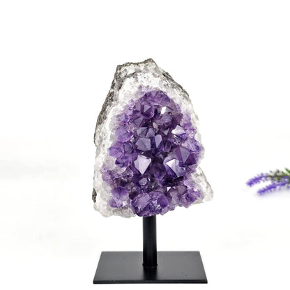 Amethyst crystal cluster on a black stand with a white background