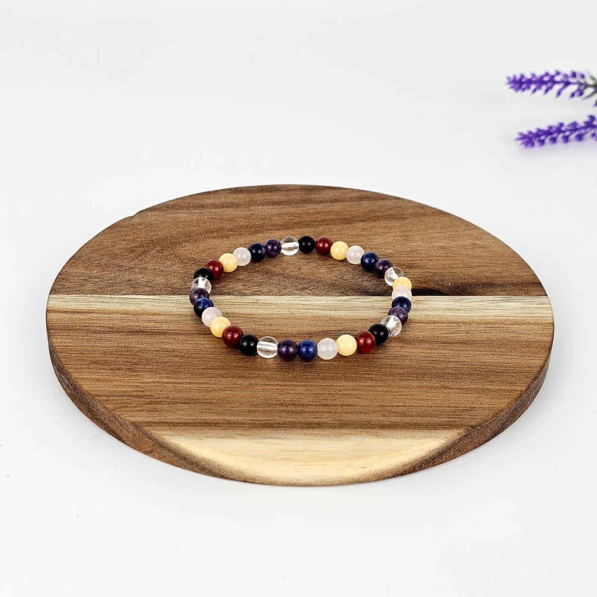 Beaded chakra bracelet on a wooden round platform with a white background