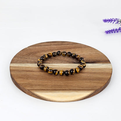 Beaded tiger's eye bracelet on a wooden plate with a white background