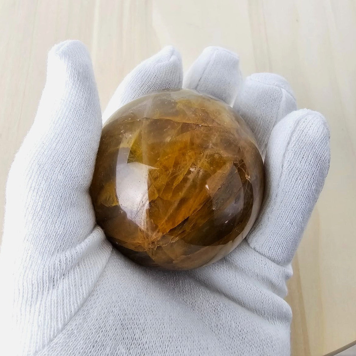 Holding a large golden healer crystal sphere against a neutral background