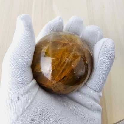 Holding a large golden healer crystal sphere against a neutral background