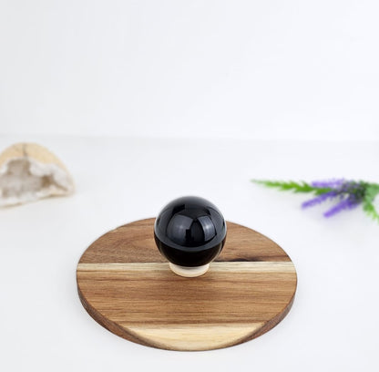Black spherical obsidian on a wooden coaster with a white background