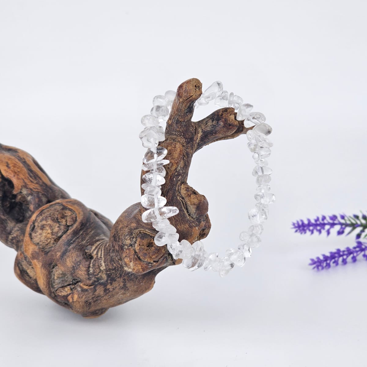 Clear quartz bracelet on a wooden branch with a white background