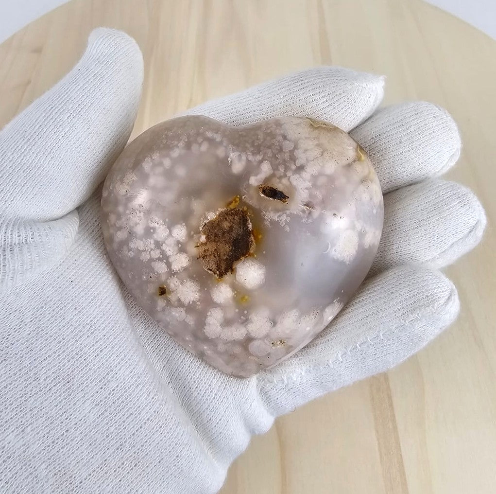 Flower agate  heart shape hold in  a gloved hand