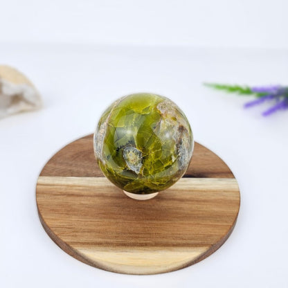 Green opal sphere on a wooden stand with a white background
