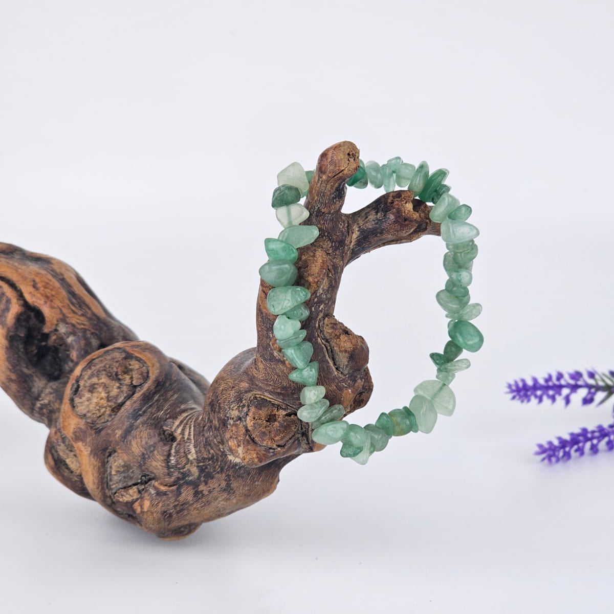 Green aventurine bracelet on a wooden branch with a white background