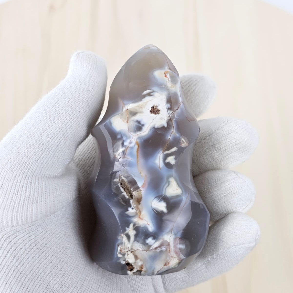 Hand holding a translucent orca agate stone with a white interior against a neutral background