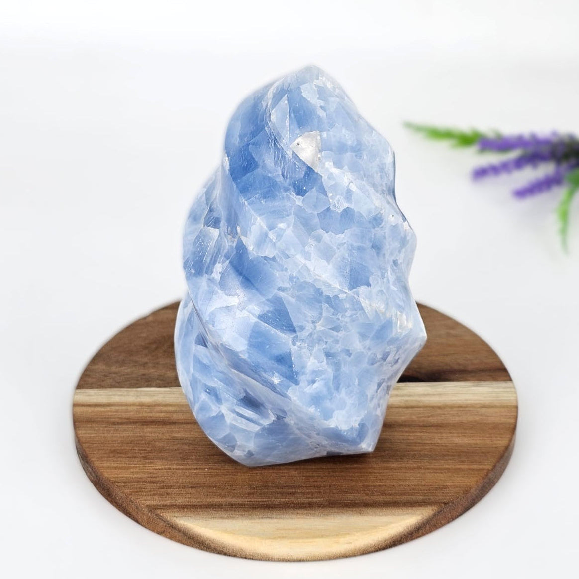 Blue calcite flame sculpture on a wooden plate and a white background