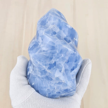 Blue calcite flame sculpture in a white gloved hand