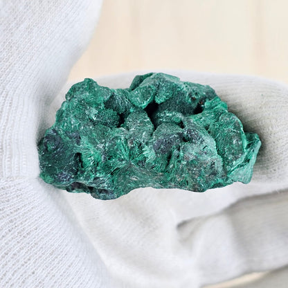 Raw fibrous malachite in gloved hand