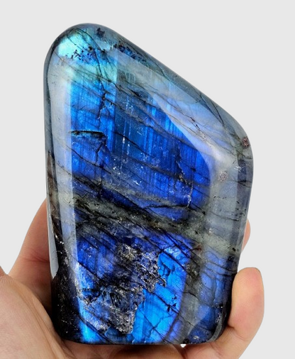 Labradorite stone held in a hand against a white background