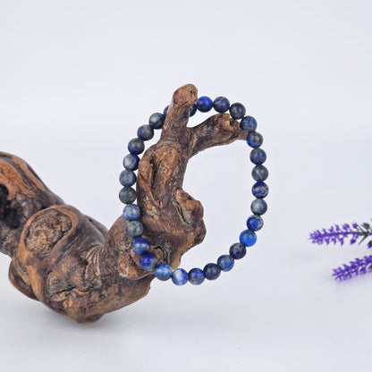 Lapis lazuli beaded bracelet on a wooden branch with a white background