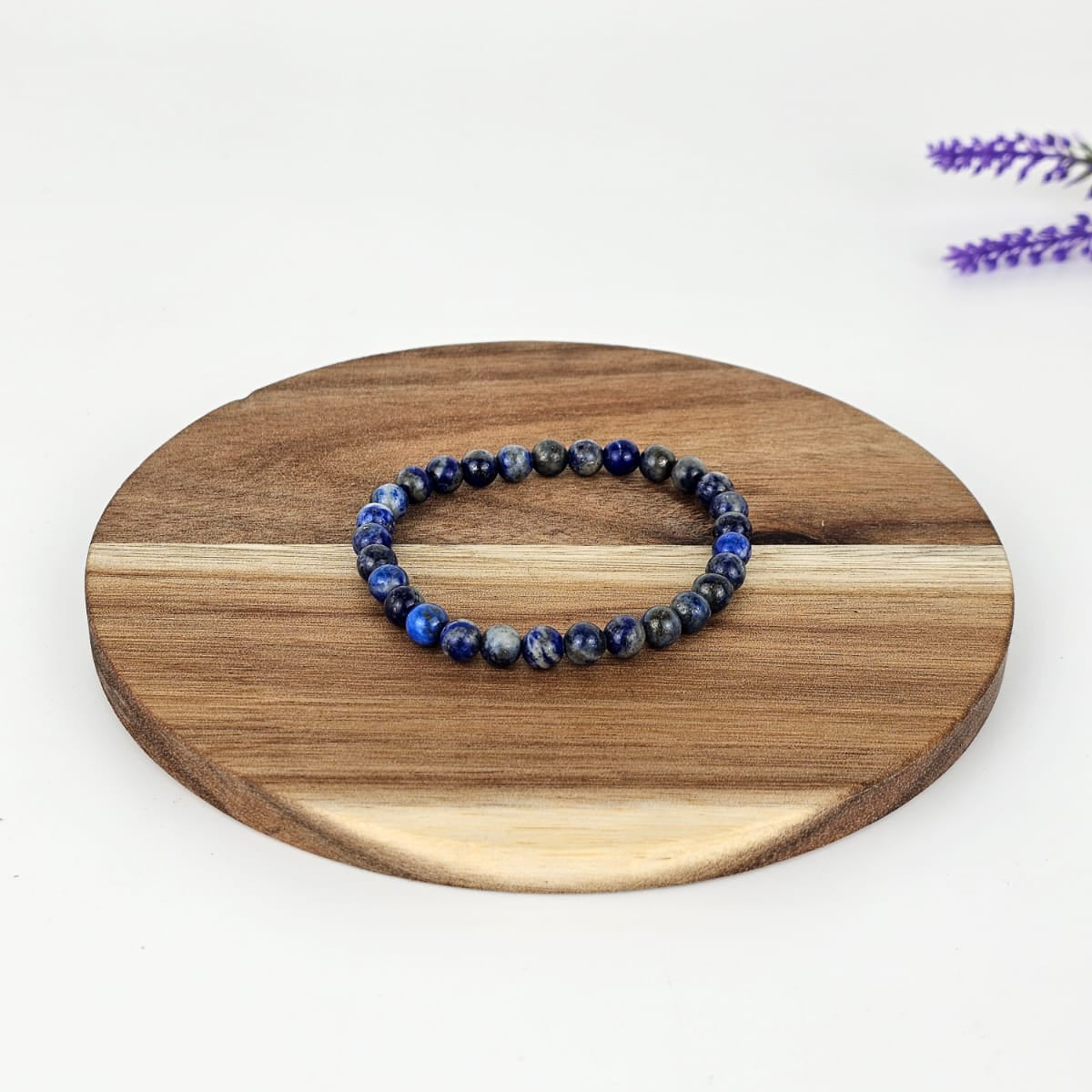 Lapis lazuli beaded bracelet on a wooden plate and a white background