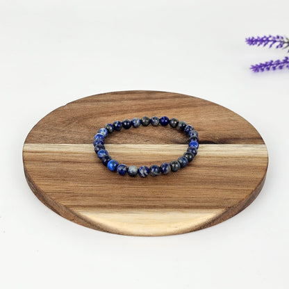 Lapis lazuli beaded bracelet on a wooden plate and a white background