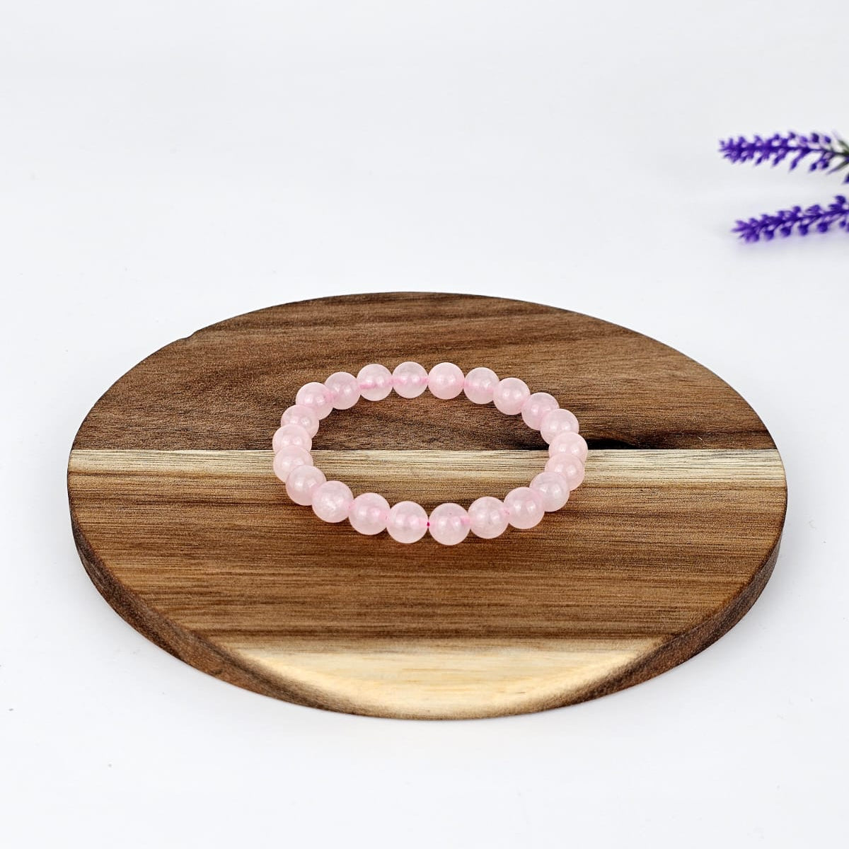 Rose Quartz beaded bracelet on a wooden plate and a white background