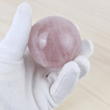Rose quartz held by a white gloved hand on a light background