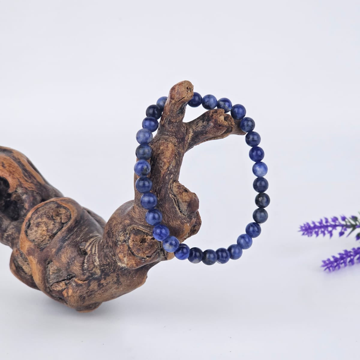 Sodalite beaded bracelet on a wooden branch with a white background