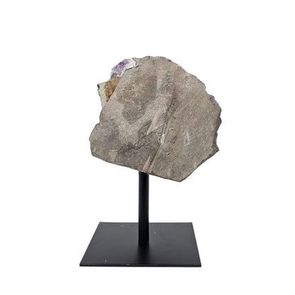 Back amethist geode on a stand against a white background
