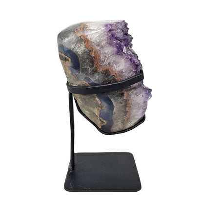 Amethyst crystal on a black stand against a white background