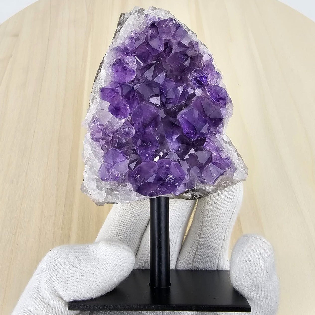 amethist cluster on stand in a gloved hand 