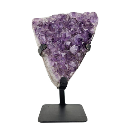 Amethyst crystal on a black stand against a white background