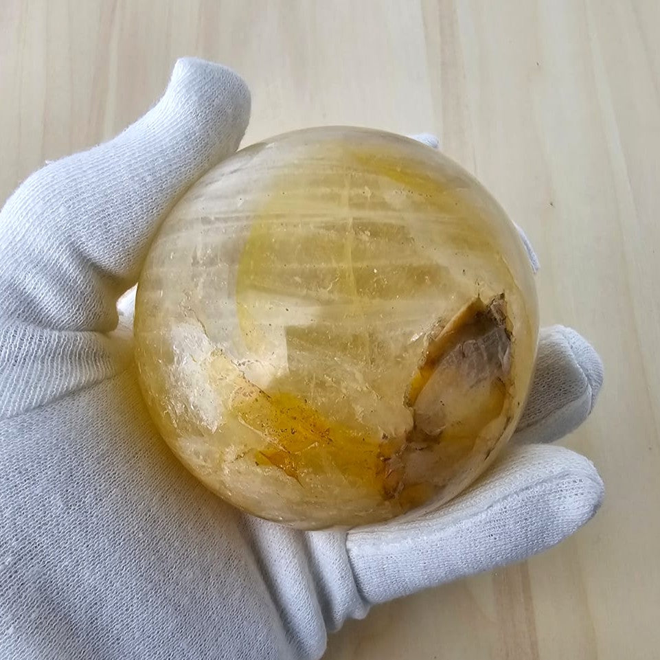 Crystal golden healer held by a gloved hand on a neutral background