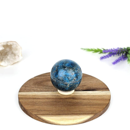 blue apatite sphere on a wooden plate and white background and a purple flower