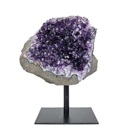 Amethyst crystal on a stand against a white background