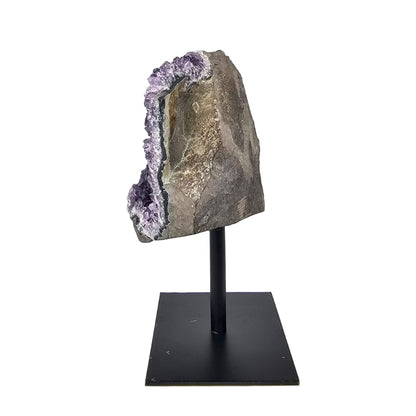 Amethyst geode on a black stand against a white background