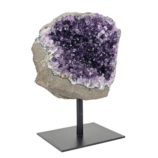 Amethyst crystal on a stand against a white background