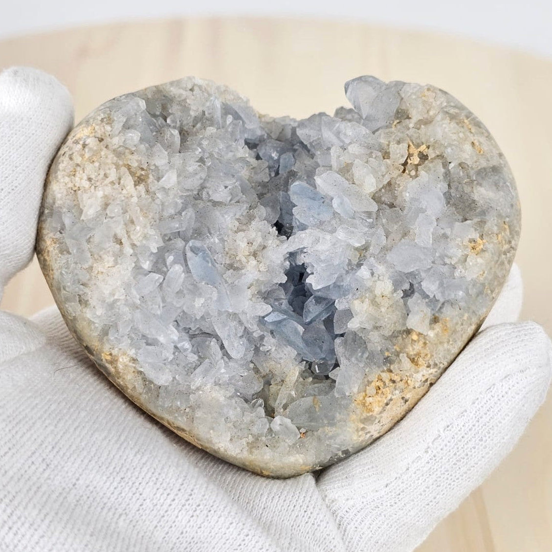 Celestite heart shape cluster in gloved hand