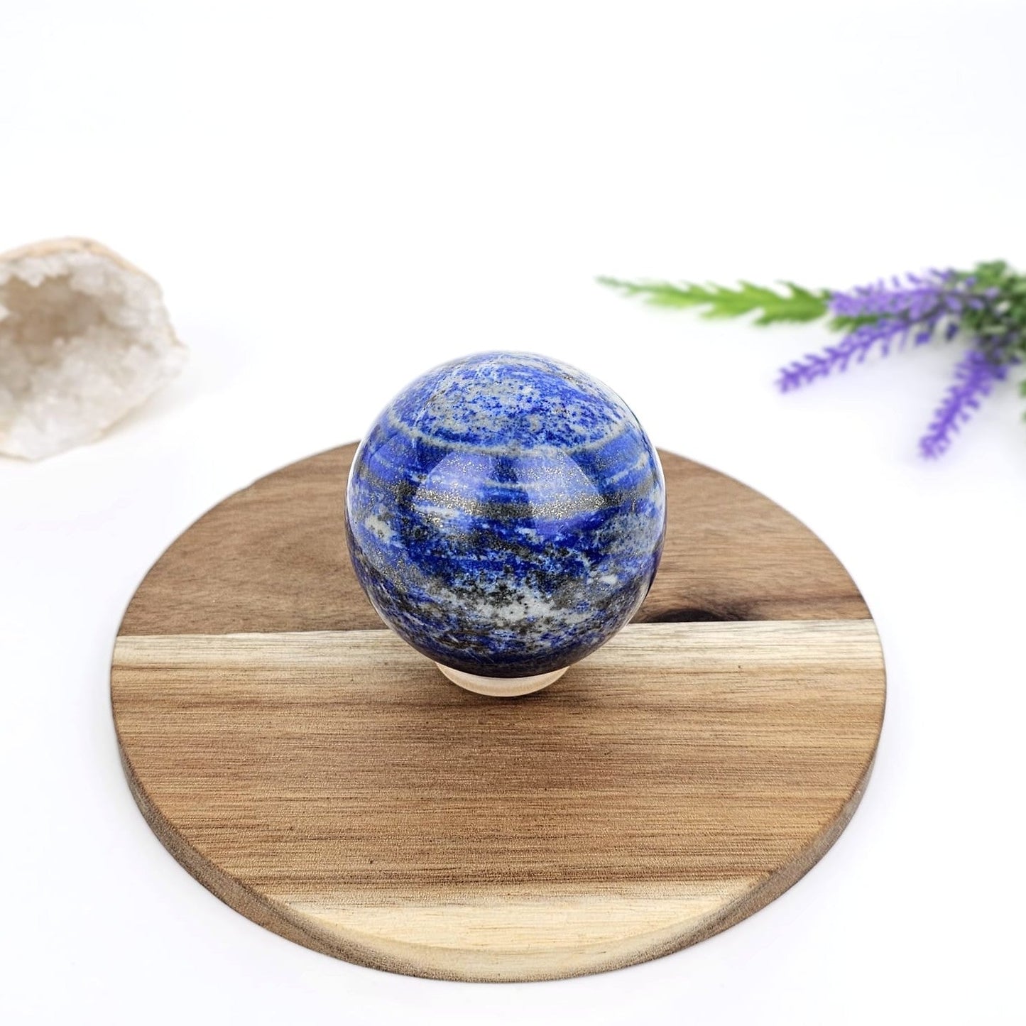 lapis lazuli sphere on a wooden stand with a white background and decorative elements.