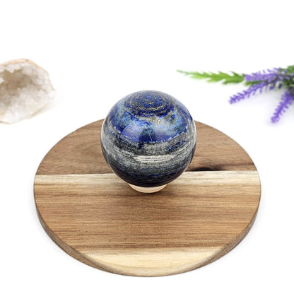 lapis lazuli crystal sphere on a wooden stand with decorative elements in the background