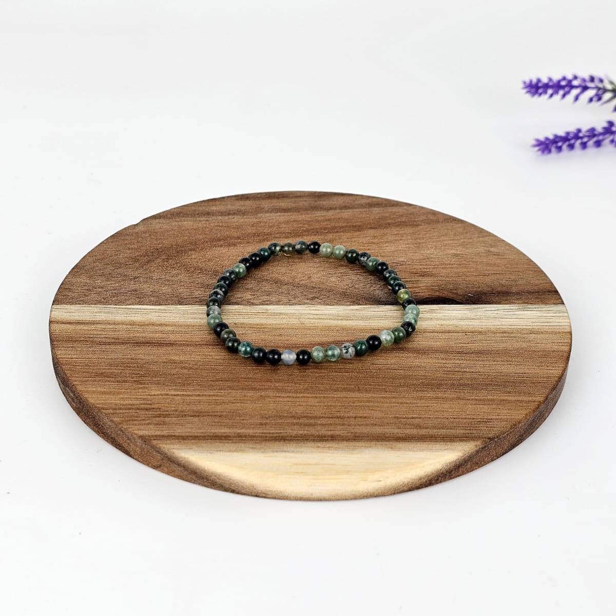 Moss agate beaded bracelet on a wooden plate and a white background