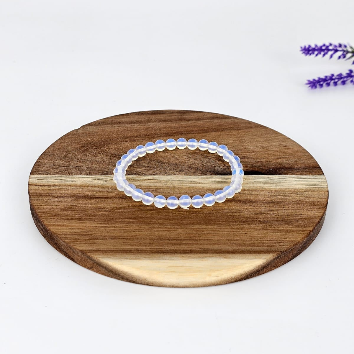 opalite beaded bracelet on a wooden plate and a white background