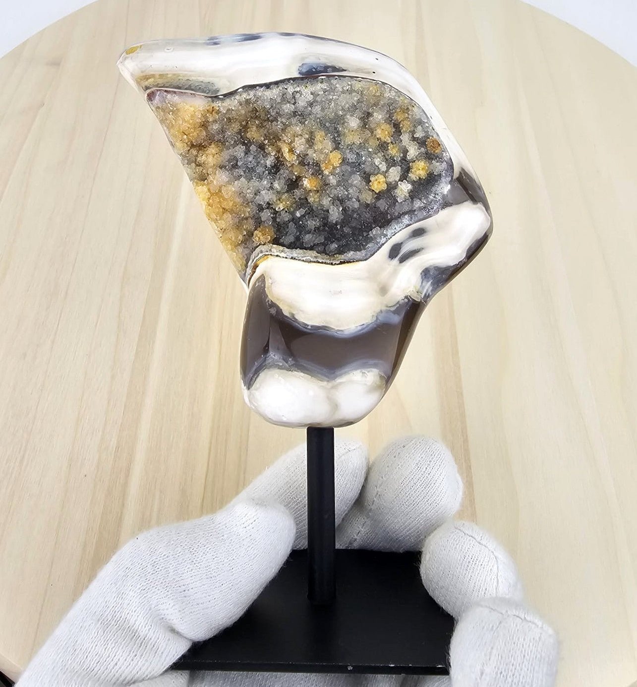 arca agate with druzy on a stand in gloved hand 