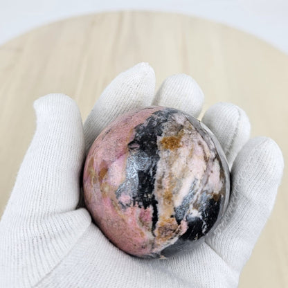 Rhodonite crystal sphere from afghanistan in gloved hand