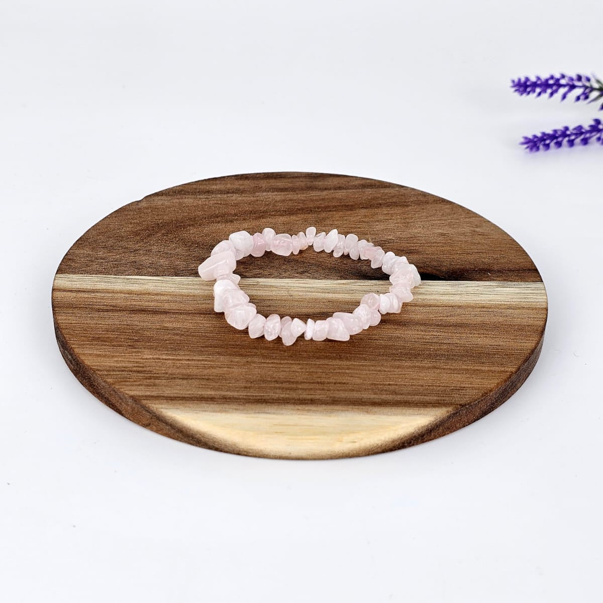 Rose quartz chip bracelet on a wooden plate and a white background