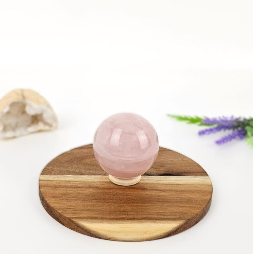 Rose quartz crystal sphere on wood
