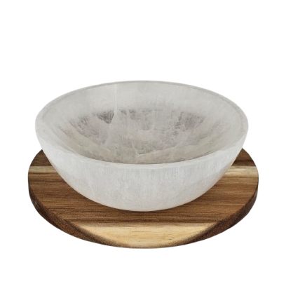 Selenite bowl on a wooden stand with a white background