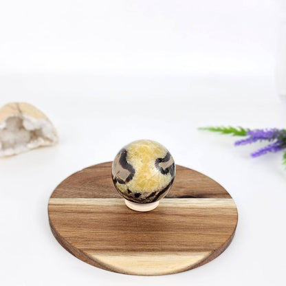 septarian sphere on a wooden stand with a white background