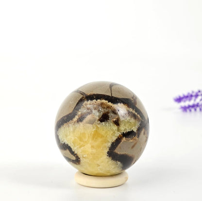 Decorative septarian sphere with brown and yellow patterns on a white background