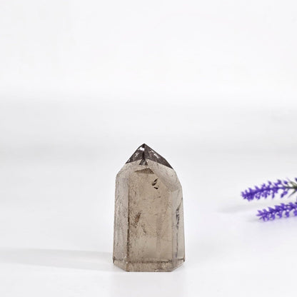 Smoky quartz point on a white background with lavender flowers